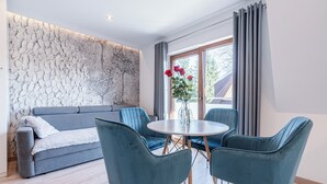 Ein modernes Wohnzimmer mit einem grauen Sofa, Türkis-farbenen Sesseln und einem runden Tisch.