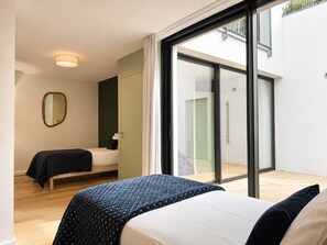 A modern bedroom with two beds, a large sliding glass door leading to a balcony, and a mirror on the wall. - The Social Liveur- Soho « Les Chartrons » (Bordeaux)