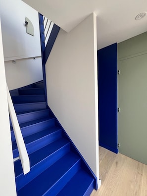 A staircase with blue steps and white handrails, leading to a door with a green wall. - The Social Liveur- Soho « Les Chartrons » (Bordeaux)