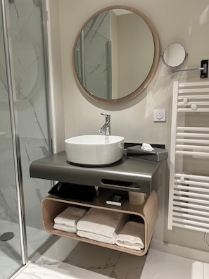 A modern bathroom with a white sink, a round mirror, and a towel rack. - The Social Liveur- Soho « Les Chartrons » (Bordeaux)