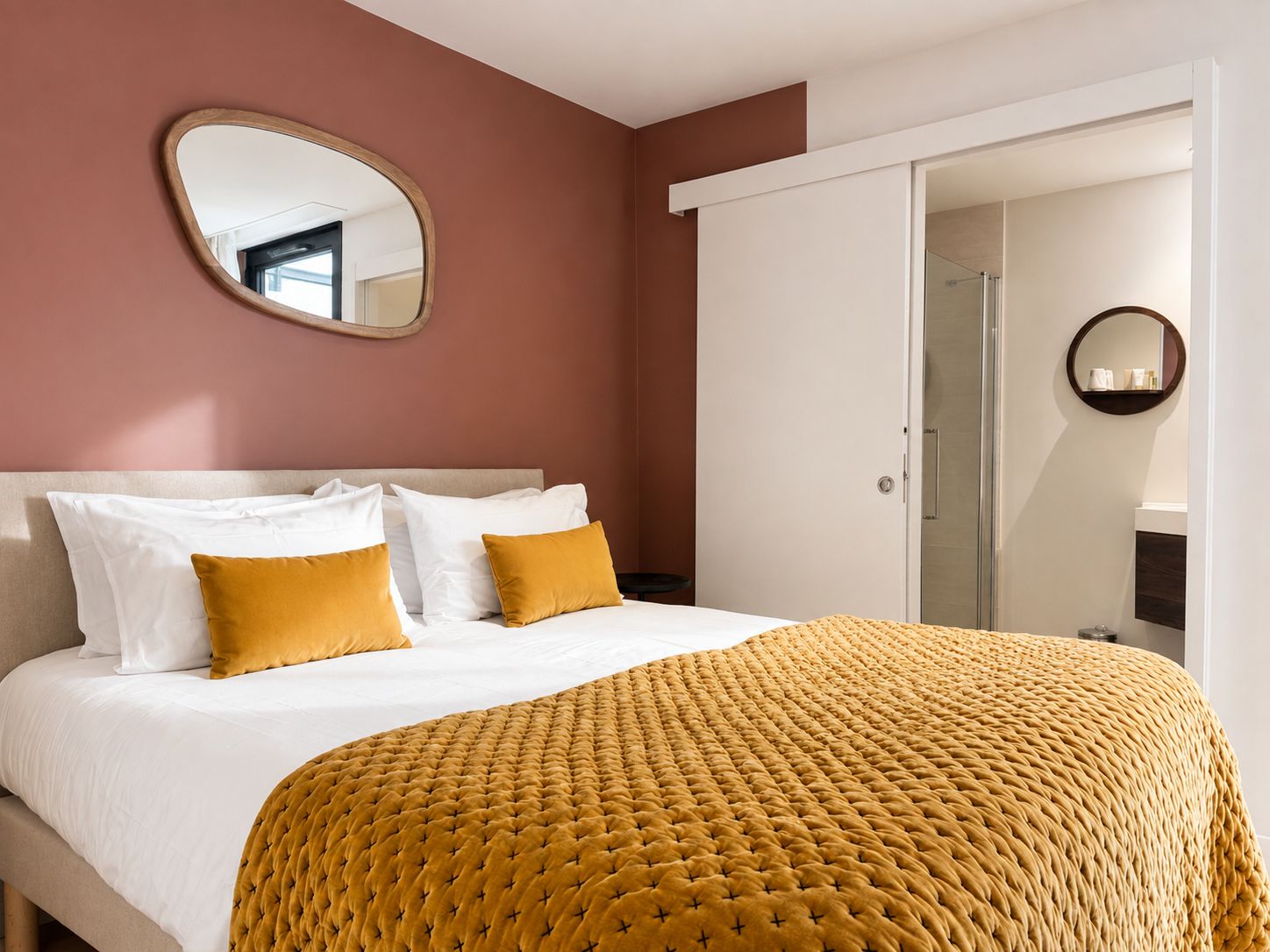 Una habitaci ón de hotel con cama, espejo y puerta que da a un baño.