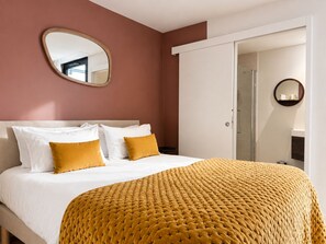 Una habitación de hotel con cama, espejo y puerta que da a un baño.