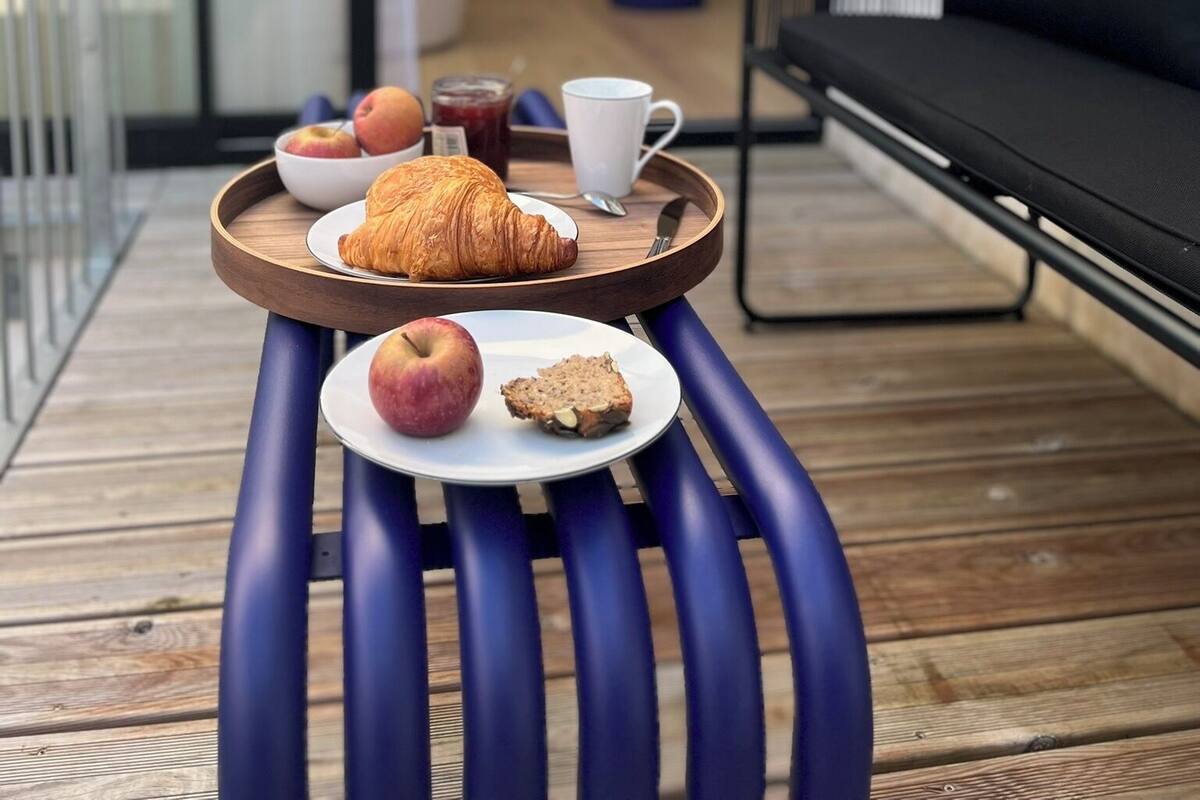 A breakfast tray with croissant, apple, and muffin on a wooden table.