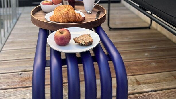 Bandeja de desayuno con croissant, manzana y muffin sobre una mesa de madera.
