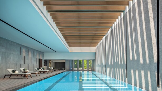 Ein moderner, überdachter Pool mit Liegestühlen und Holzbalkendecke.