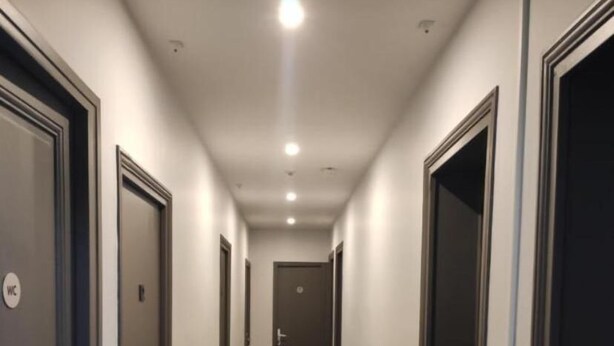 A hotel hallway with doors on both sides, a wooden floor, and a ceiling with recessed lighting. - Le Palmier (Saint-Denis)
