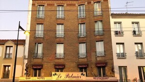 A multi-story building with a sign for "Le Palmier" hotel and restaurant. - Le Palmier (Saint-Denis)