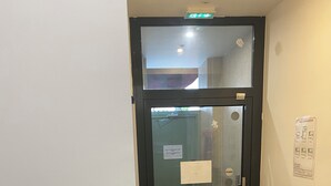 A door with a glass panel, a sign, and a fire alarm. - Le Palmier (Saint-Denis)
