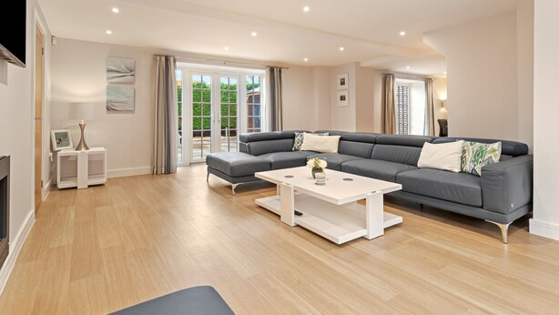 A modern living room with a grey sectional sofa, a white coffee table, and a wooden floor.