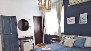 Une chambre à coucher comprenant un lit, un bureau, une armoire, un miroir rond et une fenêtre avec des rideaux.
