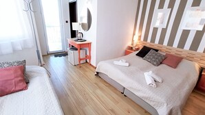 Une chambre d’hôtel avec deux lits, un bureau, un miroir et un mur à rayures.