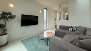 A modern living room with a flat-screen TV, a grey sofa, a small round coffee table, and a potted plant. - MitO Onomichi (Onomichi)