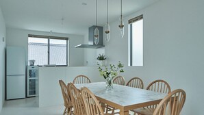 A modern kitchen with a dining table and chairs, a built-in oven, and a window with a view. - MitO Onomichi (Onomichi)