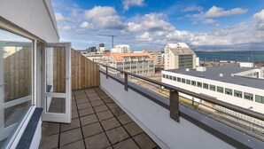 A balcony with a view of the sea and buildings. - Hlemmur Suites - Large Deluxe Studio (Reykjavík)