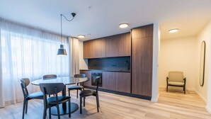 A modern kitchen with wooden cabinets, a built-in oven, and a dining area with a round table and four chairs. - Superior one bedroom apartment (Reykjavík)