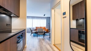 A modern hotel room with a kitchenette, a dining area with a sofa and chairs, and a large mirror. - Superior one bedroom apartment (Reykjavík)
