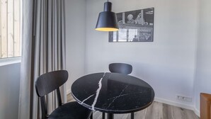 A dining area with a black table and chairs, a pendant light, and a framed picture on the wall. - Deluxe Ocean view one bedroom apartment with balcony (Reykjavík)