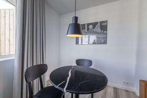 A dining area with a black table and chairs, a pendant light, and a framed picture on the wall.