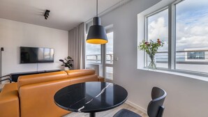 A modern living room with a sofa, a round black table, and a TV. - Deluxe Ocean view one bedroom apartment with balcony (Reykjavík)