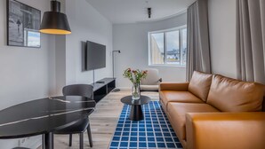 Una sala de estar moderna con un sofá, una mesa de comedor y un televisor montado en la pared.