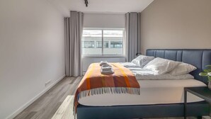 A hotel room with a bed, a window, a radiator, and a plant. - Deluxe three bedroom apartment (Reykjavík)
