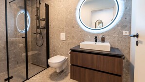 Un baño moderno con ducha envuelta en vidrio, inodoro blanco y tocador con espejo.