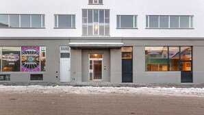 Un edificio moderno con ventanas amplias, una entrada central y un cartel publicitario de una bolera.