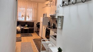 A compact kitchen with a refrigerator, microwave, and coffee machine. A small dining table with a chair is visible, and a sofa is placed near the window. - Casa Angela by Ca-sa Check (Chioggia)