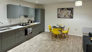 Une cuisine moderne avec des meubles gris, une table à manger avec des chaises jaunes et un tableau accroché au mur.