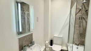 Une salle de bain moderne avec un lavabo sur colonne, des toilettes et une douche à parois de verre.