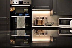 A modern kitchen with stainless steel appliances, including a microwave, toaster, and oven.