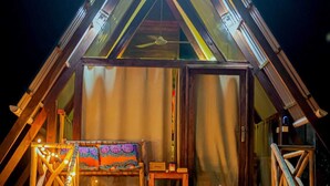 A triangular wooden cabin with a porch, a bench, and a table. - Cozy A-frame Retreat in Zanzibar Nungwi Leo Glamping (Nungwi)