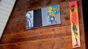 A person reading a book in a room with wooden walls, a bed with white bedding, and artwork on the wall. - Cozy A-frame Retreat in Zanzibar Nungwi Leo Glamping (Nungwi)
