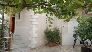 A building with a staircase leading to a door, a potted plant, and a bicycle. - Magic Ionian Apartments & Rooms (Himarë)