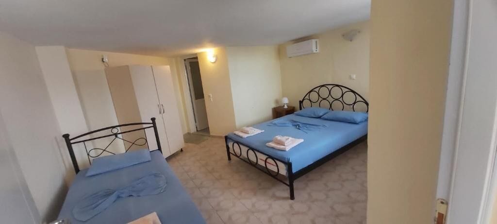 Un dormitorio con dos camas, un armario y una mesita de noche con lámpara.