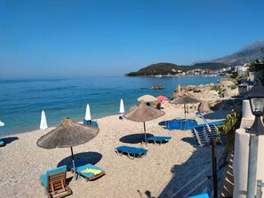 På stranden, vit sandstrand, solstolar och parasoller