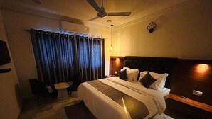 A hotel room with a large bed, a ceiling fan, a desk, and a chair. - Hotel 7 Cr (Vadodara)