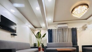 A modern living room with a sofa set, a coffee table, and a TV mounted on the wall. - Hotel 7 Cr (Vadodara)