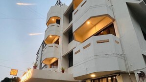 A multi-story hotel with balconies, a sign indicating it is a 7CR hotel, and potted plants in the entrance area. - Hotel 7 Cr (Vadodara)
