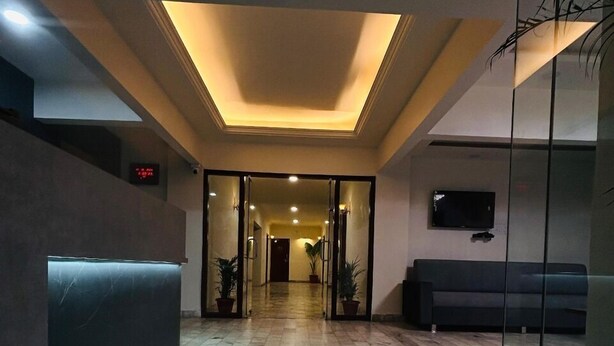 A modern lobby with a tiled floor, a reception desk, a seating area, and a glass partition. - Hotel 7 Cr (Vadodara)