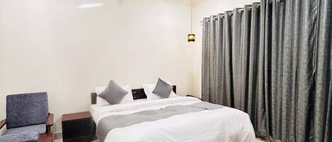 A bedroom with a bed, a chair, a nightstand, a ceiling fan, and a red rug.