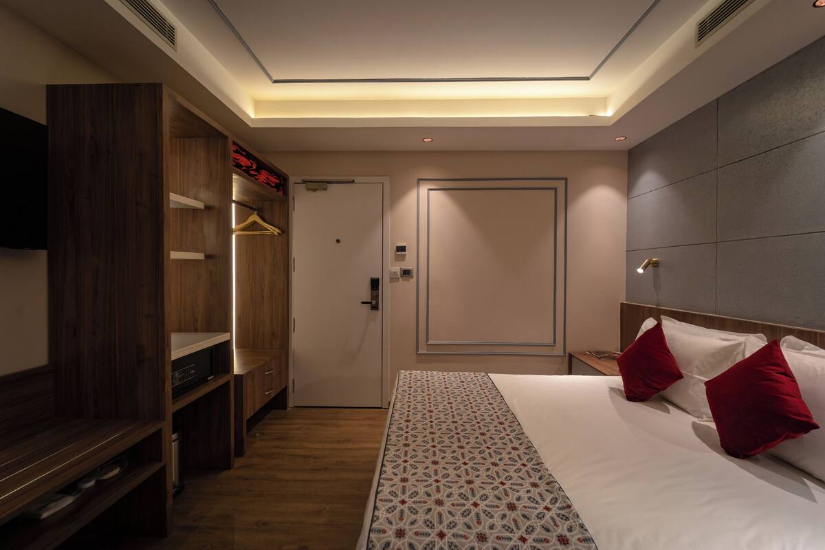 A hotel room with a bed, a wardrobe, a mirror, and a door.