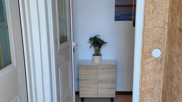 Un pasillo con un mueble de madera, una planta en maceta y un cuadro en la pared.