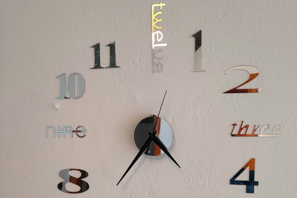 Une horloge murale avec des chiffres et des mots écrits dans différentes polices et couleurs.