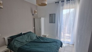 A bedroom with a bed, a nightstand, a wardrobe, a mirror, and a window with curtains. - Charming Villa 4 pers swimming pool terrace 600 m from the beach (Belgodère,)