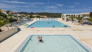 A swimming pool with clear blue water, surrounded by lounge chairs and a view of hills in the background. - Charming Villa 4 pers swimming pool terrace 600 m from the beach (Belgodère,)