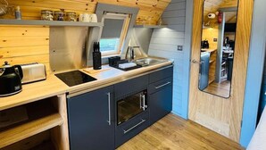 A compact kitchen with wooden ceiling, a built-in oven, and a sink.