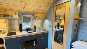A compact kitchen with modern appliances, a wooden ceiling, and a large mirror.