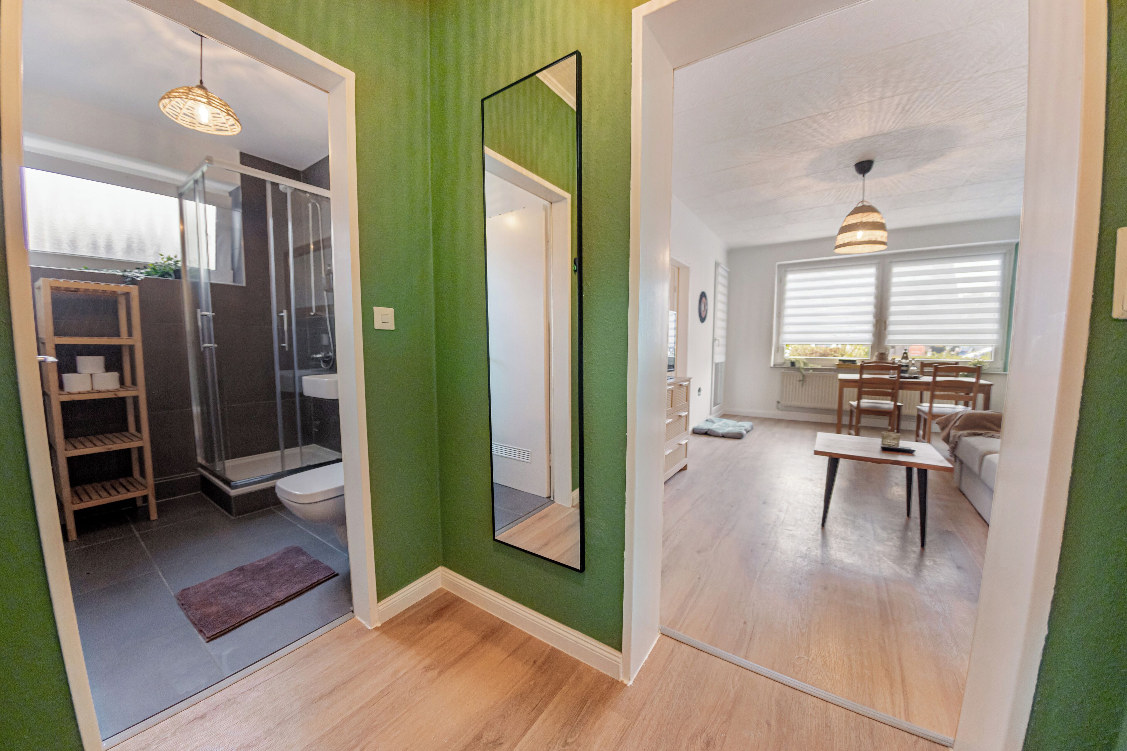 Un baño moderno con ducha de vidrio, tocador de madera y un espejo grande.