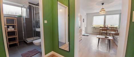Un baño moderno con ducha de vidrio, tocador de madera y un espejo grande.